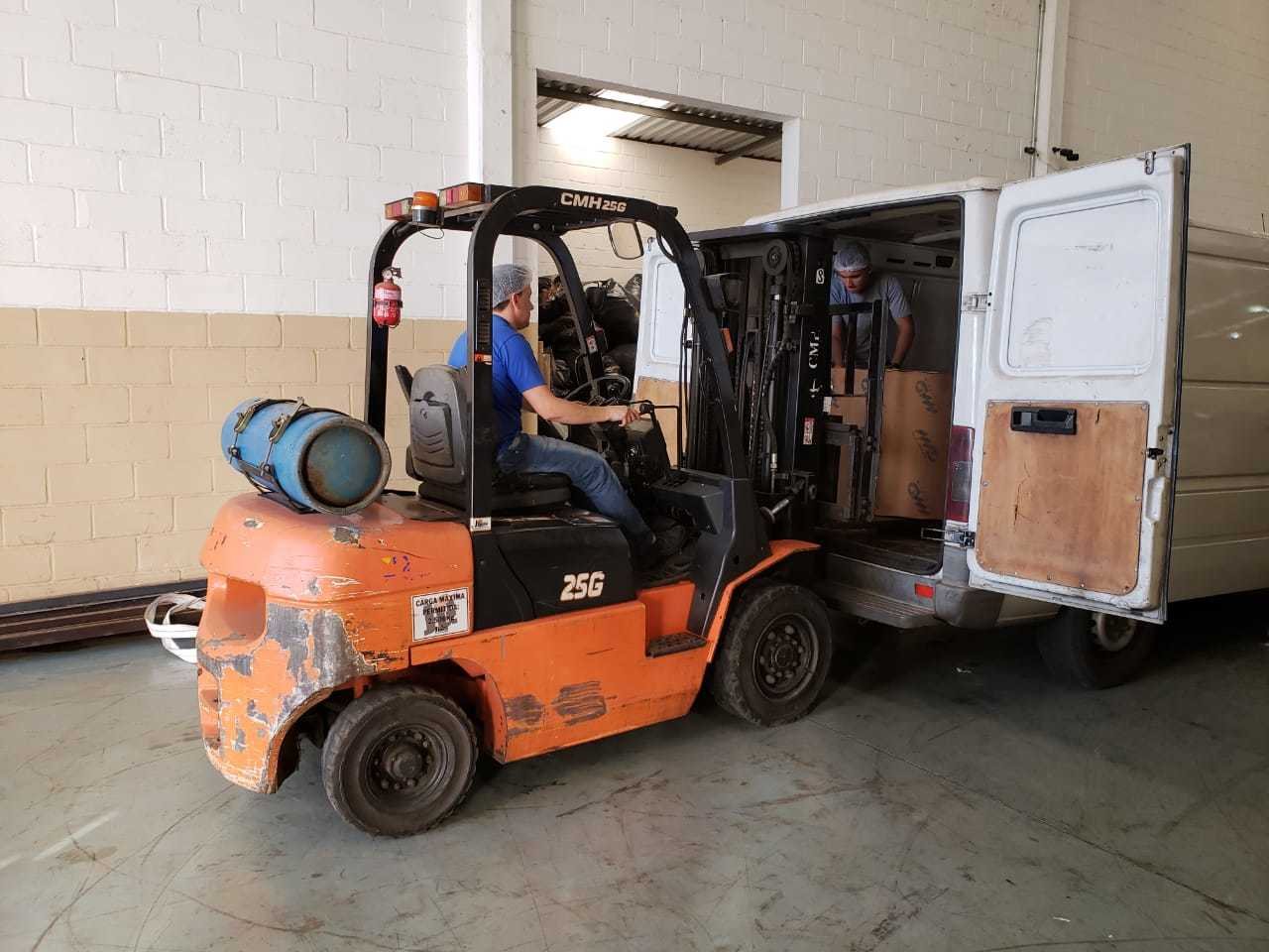 Empilhadeira carregando caixas no veículo de entrega da Limerfilmes